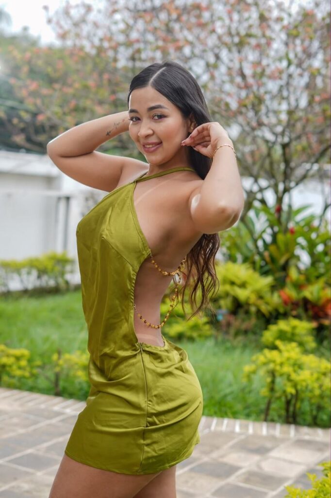 Yuliana poserer for «Escorts Malaga» i en kort, olivengrønn kjole