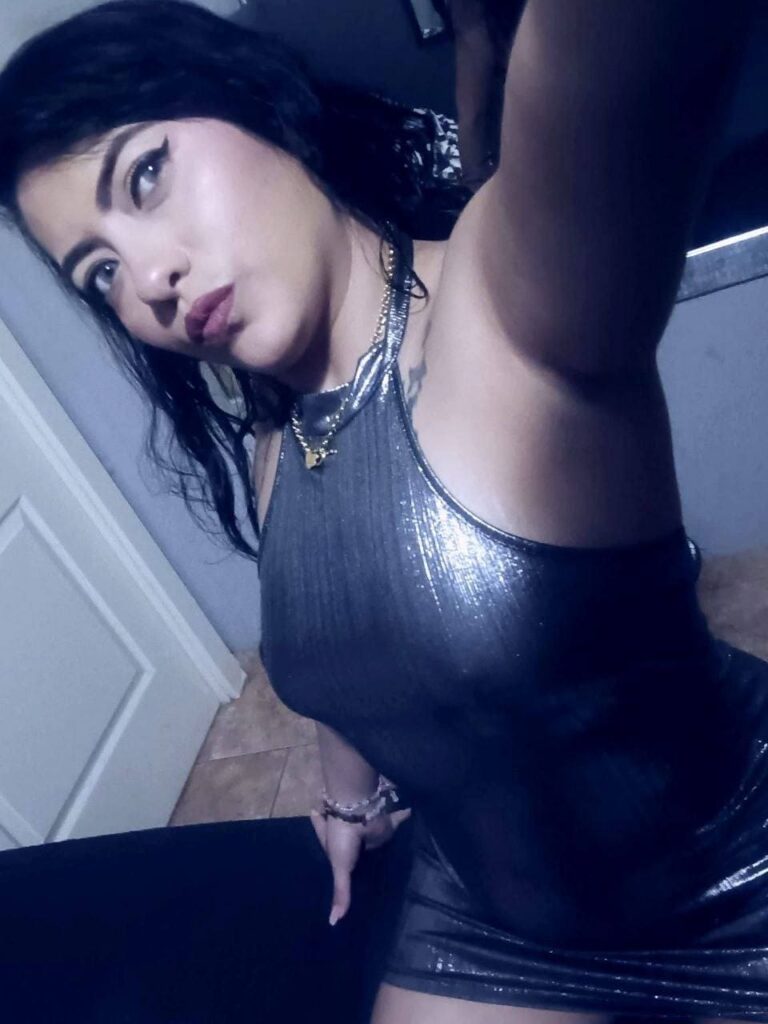 Camila, escort bærer en stram kjole med høy hals i metallicgrått i Malaga