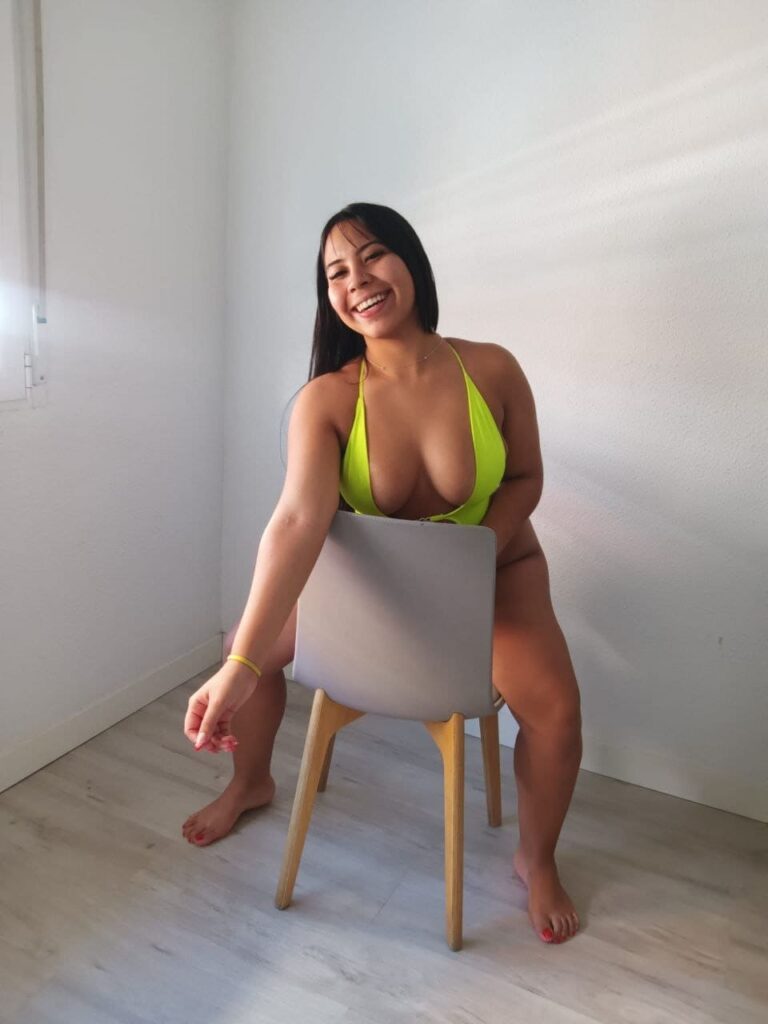 Nathy, escort de 22 años está sentada sobre una silla sonriendo en Malaga